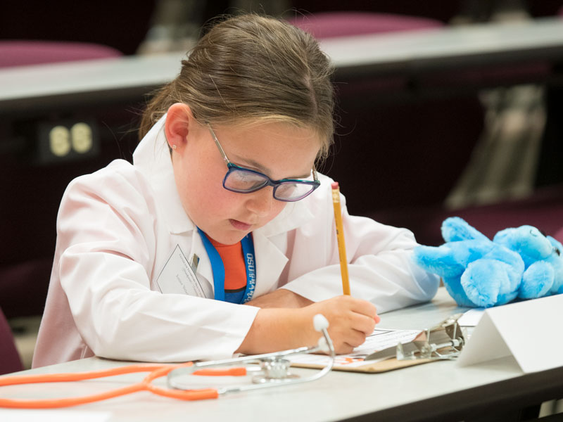 Child at grandparent university writing on worksheet